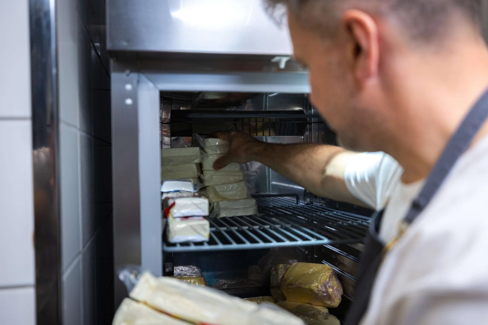Szakács alapanyagokat pakol a hűtőkamrában