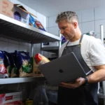 Séf laptoppal ellenőrzi a raktári alapanyagokat